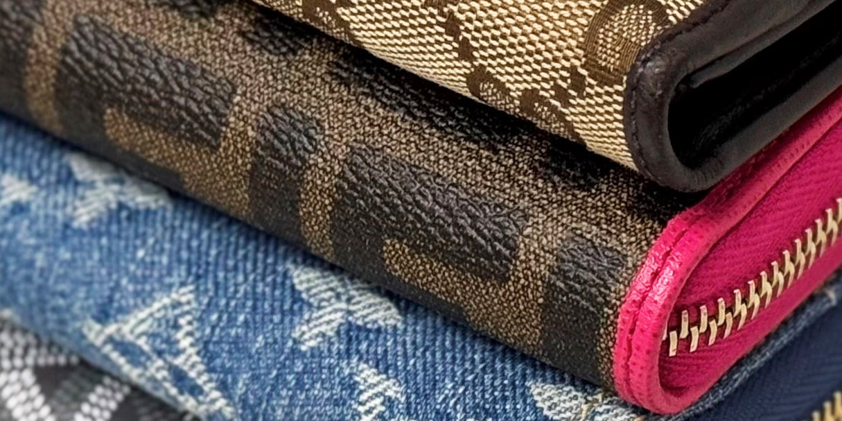 A stack of patterned wallets from Gucci, Fendi, Louis Vuitton, Goyard, and Chanel.