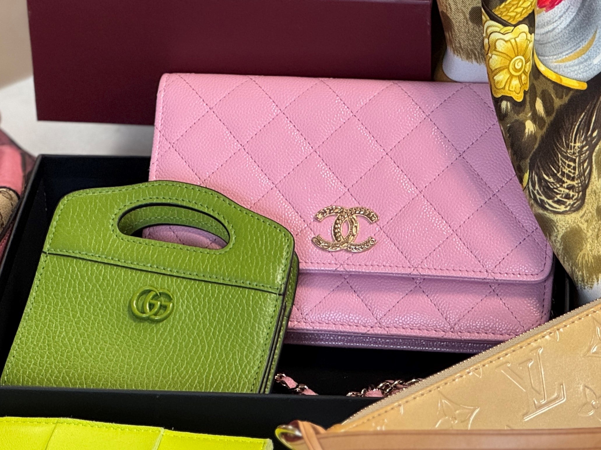 Pink quilted Chanel and a green leather Gucci bag in a black box.